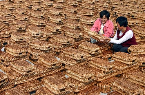 2005年10月18日,在安徽省阜南縣城鎮(zhèn)化移民新村王家壩村柳編廠,兩名女工正在翻曬柳編制品。移民新村的良好環(huán)境吸引來外商投資,解決了近百名新村農(nóng)民就業(yè)問題。不斷崛起的城市群落,日益繁榮的城市經(jīng)濟,加速改善的城市生活……變化,緣于一個巨大的跨越:中國城鎮(zhèn)化60年間以不可阻擋之勢迅猛向前。它所蘊涵的是,中國經(jīng)濟規(guī)模擴張、工業(yè)化步伐加快推進、城市功能迅速提高的輝煌歷程。新華社發(fā)