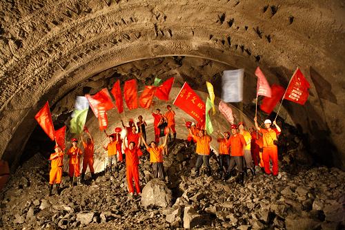 7月24日,在宜巴高速公路控制性工程界嶺隧道右線南北匯合處,建設(shè)者揮舞彩旗慶祝右洞貫通。 新華社發(fā)(文振效 攝)