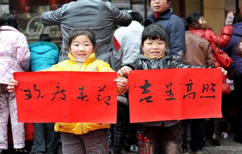 1月26日,在江西樂平市街頭,兩名小女孩展示書法家義務(wù)書寫的春聯(lián)。當(dāng)日,江西樂平市文聯(lián)、書法家協(xié)會聯(lián)合組織近20名書法家在江西樂平市街頭義務(wù)為群眾寫春聯(lián),送上新春祝福。新華社發(fā)(朱定文 攝)