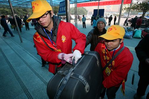 1月26日,廣西桂林市大學(xué)生志愿者在火車站幫助旅客運(yùn)行李。新華社發(fā)(唐侃 攝)