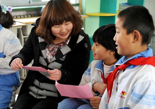 3月5日,在濟(jì)南市文苑小學(xué),山東大學(xué)青年志愿者石培和在此就讀的農(nóng)民工子女交流。新華社記者 徐速繪 攝