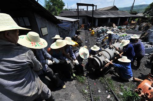 7月4日,救援隊員在井口搬運救援設(shè)備,準備運到井下。新華社記者 李斌 攝