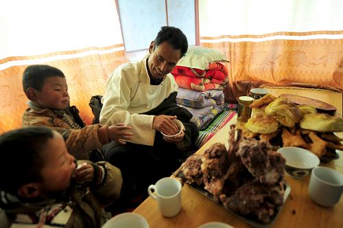 2月22日,在甘肅省甘南藏族自治州合作市佐蓋曼瑪鄉(xiāng)地瑞村,豆格扎西(右)在自家危房改建的新房內(nèi)和兩個孫子吃午飯。新華社記者張錳攝
