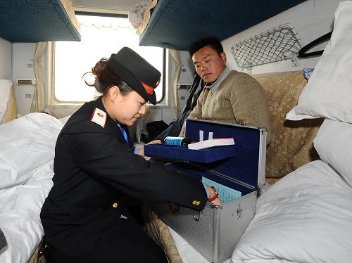 2月12日,在K892次列車上,列車員董文婷(左)在給旅客送藥。新華社記者 燕雁 攝