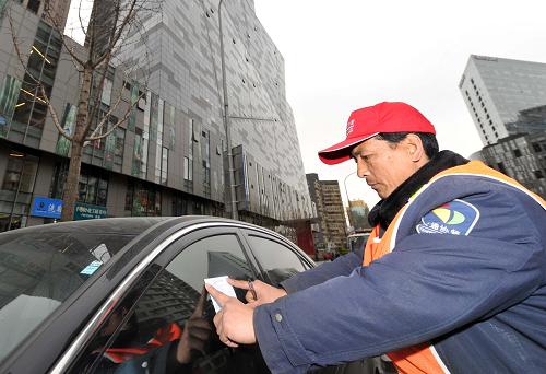 4月1日,北京CBD區(qū)域內(nèi)的一位交通協(xié)管員將“違章停車告知單”貼在一輛違章停放的車輛上。新華社記者 公磊 攝
