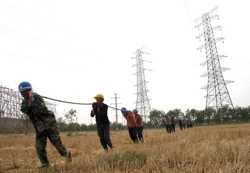 6月21日,工人在河北省滄州市220千伏獅城變電站建設(shè)工地架設(shè)輸電線路。新華社發(fā)(傅新春 攝)