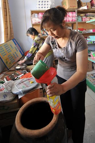 在山西省運城市太陽鄉(xiāng)下王尹村便民連鎖商店里,一位村民在打醬油(6月20日攝)。新華社記者 詹彥 攝