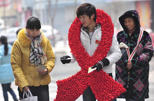 11月26日,在沈陽市內(nèi)的商業(yè)街,大學生志愿者挎著用數(shù)千小紅絲帶制作的預防艾滋病標志,向市民發(fā)放艾滋病宣傳材料。新華社發(fā)(田衛(wèi)濤 攝)