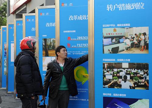 12月2日,重慶市民心家園內(nèi),市民在農(nóng)轉(zhuǎn)城展板前瀏覽。 當(dāng)日,重慶綦江縣三角鎮(zhèn)農(nóng)民胡本華從重慶市副市長童小平手中接過城鎮(zhèn)居民戶口簿,將戶籍轉(zhuǎn)入北部新區(qū)。胡本華成為重慶從2010年8月啟動戶籍制度改革以來,第300萬名自愿轉(zhuǎn)戶進(jìn)城的“新市民”。 新華社記者 陳誠 攝