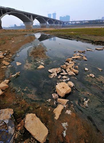 長(zhǎng)沙湘江橘子洲大橋附近一處污水排放口的污水已經(jīng)將干涸的河床沖刷出一條溝壑(1月6日攝)。新華社記者 龍弘濤 攝