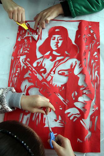 2月29日,福建莆田市荔城區(qū)第三實驗小學(xué)的兩名學(xué)生在聯(lián)合制作剪紙作品《雷鋒站崗》。新華社發(fā)(林劍冰 攝)