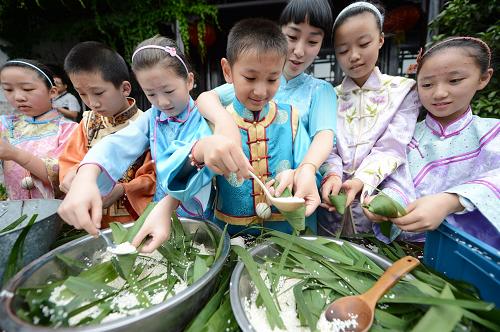 6月23日,在江蘇省揚州市何園,“小翰林”與何園景區(qū)導(dǎo)游“何園千金”一起包粽子。新華社發(fā)(孟德龍 攝)