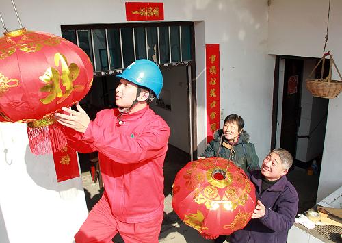 2月4日,長興縣供電局工人為長興縣李家巷鎮(zhèn)凌家濱村居民凌順茍(右下)掛上紅燈籠,共賀新春。新華社記者 徐昱 攝