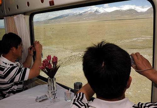 5月19日,兩位旅客在拍攝窗外西藏美麗的風(fēng)光。北京鐵路局北京客運(yùn)段京藏車隊值乘的T27/28次列車從2006年7月1日開通以來,到今年5月1日已安全運(yùn)行1446萬公里,運(yùn)送旅客528萬人次,架起了藏漢民族團(tuán)結(jié)的橋梁。新華社記者 唐召明 攝