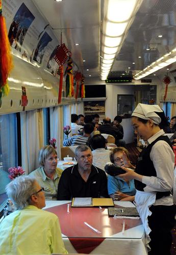 5月18日,京藏車隊第五乘務(wù)組餐車長韓莉莉(右)在為旅客提供點(diǎn)菜服務(wù)。新華社記者 唐召明 攝