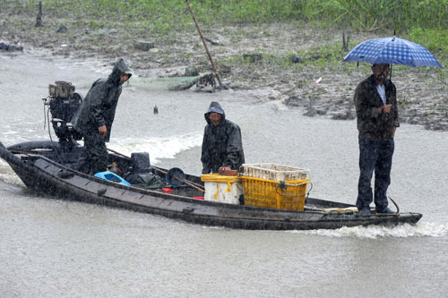 6月4日,漁民在洪湖中間的河道里冒雨行船。新華社記者 郝同前 攝