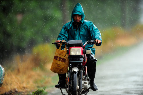 6月4日,一位漁民在洪湖邊騎著摩托車冒雨趕路。新華社記者 郝同前 攝