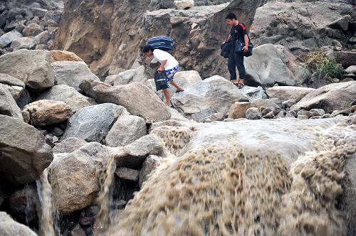 6月10日,兩位湖南岳陽臨湘市詹橋鎮(zhèn)觀山村村民穿行山洪沖積的石堆。新華社記者 趙眾志 攝