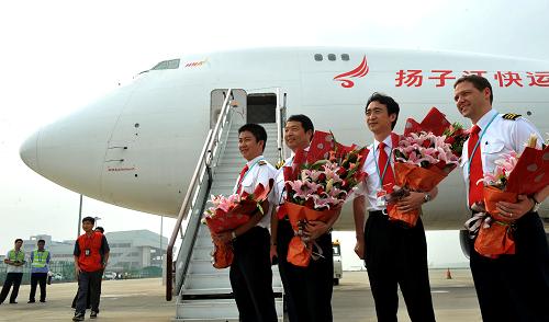 7月30日,在河南省鄭州市新鄭國際機場,揚子江快運航空有限公司參加洲際新航線首航的機組人員手捧鮮花,在飛機前合影留念。新華社發(fā)(丁友明 攝)