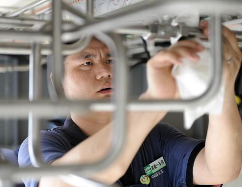 8月12日,長客工人在總組裝間清理生產(chǎn)線上的高速動車組列車。新華社記者 林宏 攝