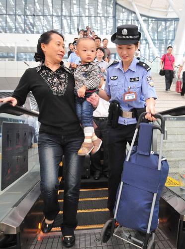 9月27日,武漢鐵路乘警邱莉華(右)幫助乘客進(jìn)站登車。新華社記者 程敏 攝