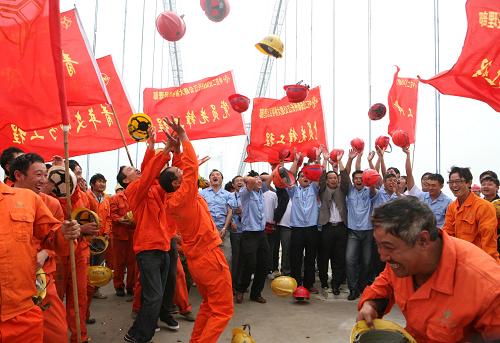 9月28日,在江蘇泰州長江大橋施工現(xiàn)場,工人們把帽子拋向空中,慶祝大橋全線合龍。新華社發(fā)(顧俊 攝)