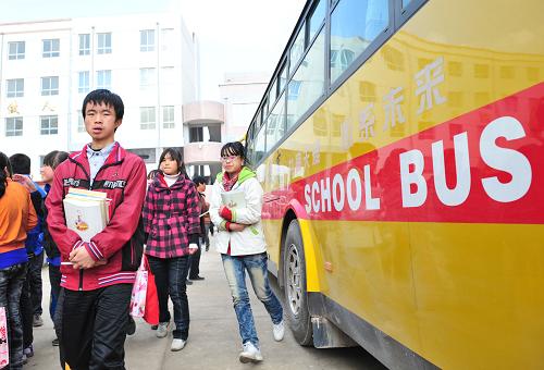 11月18日中午,甘肅省慶陽市西峰區(qū)黃官寨實驗學(xué)校的學(xué)生從校車旁經(jīng)過。每到星期五中午,學(xué)校會免費把1500多名平時寄宿學(xué)校的中小學(xué)生安全送回到幾十公里外的家中。甘肅省西峰區(qū)政府花費1100多萬元購置了22輛專門定制的校車,于2009年9月投入運營使用。校車構(gòu)架和機械性能、保險性能等均優(yōu)于普通客車,并且車窗下部為全封閉,配備有暖氣和空調(diào),安裝了GPS導(dǎo)航系統(tǒng)和時速60公里限速裝置。黃官寨實驗學(xué)校還專門擇優(yōu)招聘了持A1駕照的司機,最大可能為學(xué)生提供安全保障。新華社記者 梁強 攝