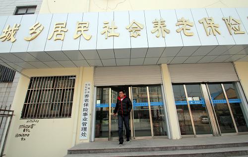 12月14日,一名辦理完城鄉(xiāng)居民社會養(yǎng)老保險的居民走出山東省臨沂市郯城縣城鄉(xiāng)居民社會養(yǎng)老保險服務(wù)大廳。新華社發(fā)(張春雷 攝)