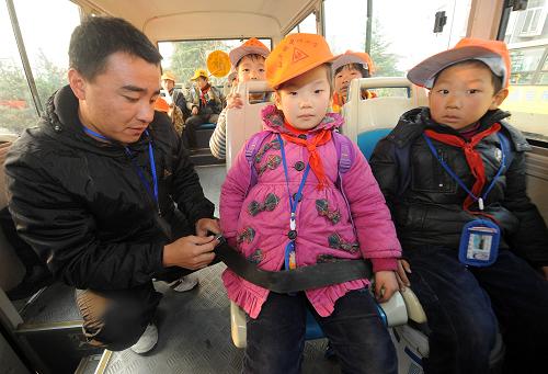 12月14日,長興縣和平鎮(zhèn)中心小學的隨車老師鄒德建(左)給乘坐校車的孩子們系好安全帶。新華社記者 徐昱攝