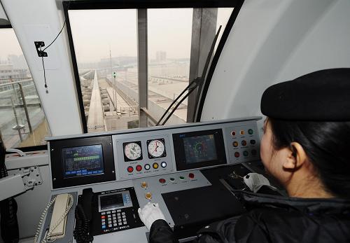 12月29日,一名駕駛員駕駛?cè)柧€列車駛向江北機場,以試驗線路通行狀況。新華社記者 李健 攝