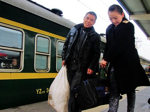1月28日,在四川達州火車站,客運員張?zhí)m(右)協(xié)助南下福建省泉州市務工的達州市達縣農(nóng)民周樹全搬運行李。 新華社發(fā)(鄧良奎 攝)