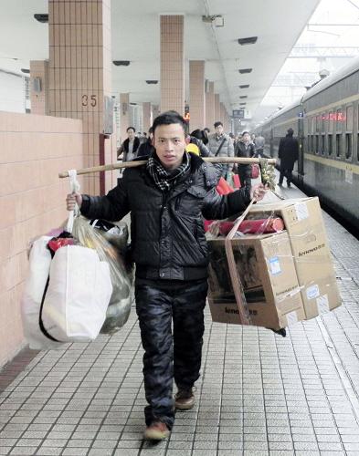 1月28日,在杭州火車站,一名旅客肩挑電腦與行李返回杭州。新華社發(fā)(龍巍 攝)