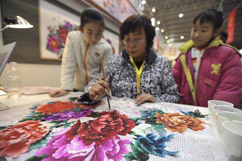 2月5日,在中國非物質(zhì)文化遺產(chǎn)生產(chǎn)性保護(hù)成果大展上,河北蔚縣剪紙藝人周淑英(中)在為剪好的紙樣上色。新華社發(fā)(劉長龍 攝)