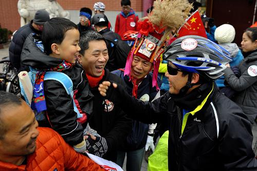 2月12日,在上海交大門口,一位為此次公益活動(dòng)捐出壓歲錢的孩子在爸爸的陪同下為吳浩斌(右)送行。新華社發(fā)(湯顯平 攝)