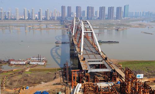 俯瞰雄姿初現(xiàn)的長沙市福元路湘江大橋(2月19日攝)。近日,長沙市福元路湘江大橋第二跨鋼拱梁完成鋼結(jié)構(gòu)拼裝,全部頂推到位。長沙福元路湘江大橋全長約3575米,其中越江段約1435米。主橋的3個鋼拱如提籃一般將大橋“提”起,每跨鋼拱長210米、重約4000噸,三跨總重超過1萬噸,通過步履式平移頂推設(shè)備從大橋一端頂推到位。目前,大橋施工方正加緊第三跨鋼拱梁拼裝,預(yù)計到4月底,3個鋼拱將全部頂推到位,實現(xiàn)主橋合龍。新華社記者 龍弘濤 攝