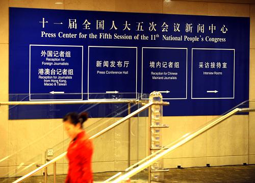 2月26日,一名工作人員從全國兩會(huì)新聞中心的標(biāo)識(shí)牌旁走過。新華社記者燕雁攝