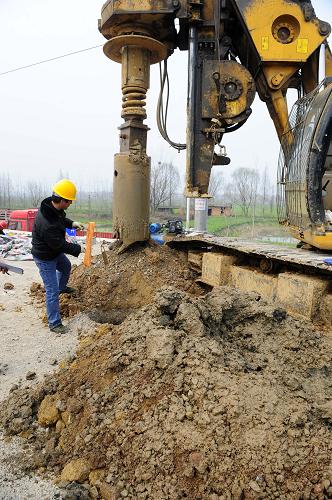 施工人員正在已經(jīng)挖開的路基深坑旁測量深度(3月12日攝)。新華社記者 郝同前 攝