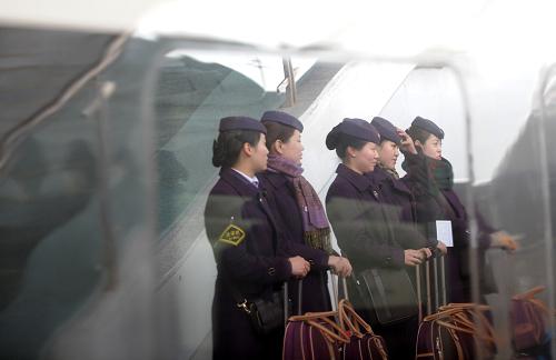3月20日,幾名高鐵列車乘務員在南京火車站工作,一輛??吭诖说臏麑幐哞F列車玻璃映出她們的身影。新華社發(fā)