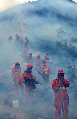 3月22日,森林武警和消防官兵在云南安寧王家灘森林火災(zāi)現(xiàn)場的隔離帶旁嚴(yán)陣以待。新華社記者 藺以光 攝