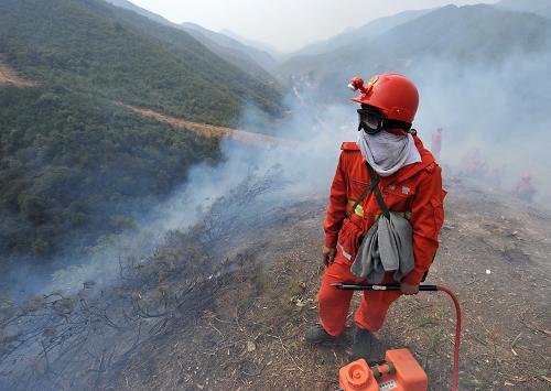 3月22日,一名森林警察在云南安寧王家灘森林火災(zāi)現(xiàn)場進(jìn)行警戒,這里距離附近的九渡村只有約400米左右。新華社記者 藺以光 攝