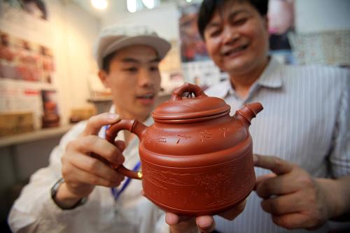 5月11日,在第二屆中國國際茶業(yè)及茶藝博覽會上,來自江蘇宜興的紫砂壺工藝師毛大步(左)向觀眾介紹其作品。當日,第二屆中國國際茶業(yè)及茶藝博覽會在北京全國農(nóng)業(yè)展覽館開幕,來自國內(nèi)外的300多家參展企業(yè)攜萬余種茶葉及茶具參展。新華社發(fā)