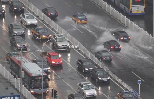 6月3日,汽車在積水的馬路上行進(jìn)。新華社記者 劉宇 攝