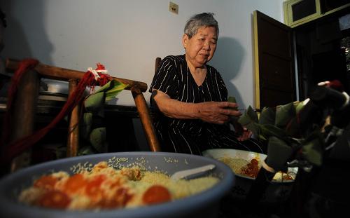 6月18日,長沙“粽子娭毑”徐桃香在家中包粽子。粽子是端午節(jié)的傳統(tǒng)食品,每年農(nóng)歷五月初,家家戶戶都會動手包粽子過端午。但隨著生活水平的提高、工作節(jié)奏的加快,如今許多城市家庭選擇在超市購買現(xiàn)成的粽子回家過節(jié),自家包粽子的習(xí)俗逐漸變淡。在長沙城南,有一位叫徐桃香的85歲老人,被街坊鄰居譽(yù)為“粽子娭毑”(長沙話奶奶的意思),每年端午前夕她家都堅持自己做粽子。徐桃香做的粽子味道純正,材料講究,因此慕名而來找老人定做粽子的人絡(luò)繹不絕。由于粽子需求量大,年事已高的她將兩個女兒培養(yǎng)成了做粽子的主力。幾十年來,徐家摸索出保證粽子味道鮮美的獨家秘方,從粽葉到糯米的干濕,再到堿和鹽的比例、包粽子的松緊、煮粽子的火候都有講究,就連蛋黃粽子選用的咸蛋,都得是剛好腌制兩個月的咸蛋。端午節(jié)的前幾天,是“粽子娭毑”最忙的時候,前來定做粽子的親朋好友絡(luò)繹不絕,最忙的時候一天要制作上千個粽子。徐家老小都聚在一起,洗粽葉、浸糯米、包粽子……屋前屋后飄蕩著粽子的清香,洋溢著端午的氣氛。新華社記者 李尕 攝