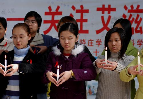 這是2005年11月30日,南京曉莊學(xué)院的幾位大學(xué)生點(diǎn)燃蠟燭為艾滋病患者以及艾滋病孤兒祈禱。 艾滋病是人類面臨的共同挑戰(zhàn)。自1981年首次發(fā)現(xiàn)至今,這一病魔已經(jīng)吞噬了2500萬人的生命。在受艾滋病煎熬的人群中,有一個(gè)特殊的群體——他們就是艾滋病致孤兒童。這些兒童大多生活在貧困地區(qū),除了承受失去父母的痛苦外,還面臨生活困窘甚至輟學(xué)的困境。他們過早地體會(huì)了孤獨(dú),親朋疏離,一些孩子的玩伴只有家里的牲畜……其生存現(xiàn)狀牽動(dòng)人心。新華社攝影記者用手中的鏡頭記錄了一些艾滋病致孤兒童的生活狀況,希望通過自己的一點(diǎn)付出和努力,帶動(dòng)更多的人投入到關(guān)愛他們的行動(dòng)中,讓歧視遠(yuǎn)離這些兒童,為他們提供一個(gè)溫暖而有尊嚴(yán)的成長(zhǎng)環(huán)境。 新華社發(fā)