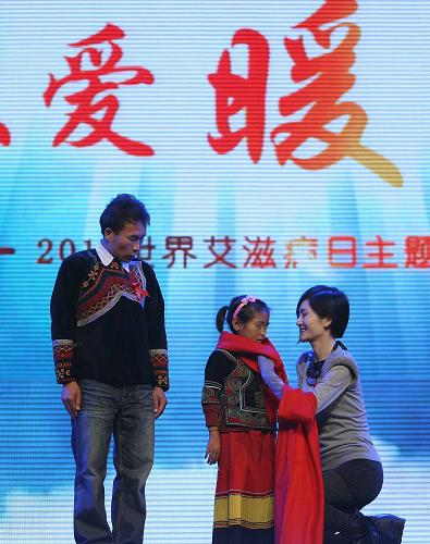 這是2011年11月30日,由全國(guó)工商聯(lián)和國(guó)務(wù)院防治艾滋病工作委員會(huì)辦公室主辦的“大愛暖中華”世界艾滋病日主題公益晚會(huì)在北京舉行,嘉賓謝娜(右一)為來自四川大涼山的艾滋病孤兒小吉克(左二)戴上紅圍巾。新華社發(fā)