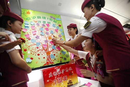6月30日,在G13次京滬高鐵上,高鐵乘務(wù)員在許愿樹上貼上祝福語。新華社記者 王申 攝