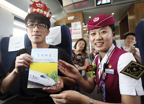 6月30日,在G13次京滬高鐵上,列車長孔維爽(右)為和京滬高鐵同天生日的旅客送上生日祝福。新華社記者 王申 攝
