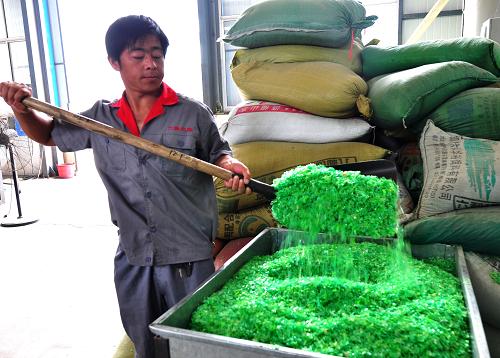 7月6日,鄒平縣再生資源生產(chǎn)廠的工人把粉碎好的廢舊塑料通過(guò)料口送到加溫爐中。新華社發(fā)(董乃德 攝)
