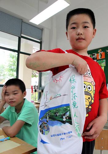7月10日,上海閔行區(qū)浦江第一小學(xué)的孫嘉遠在展示自己用舊T恤制作的環(huán)保袋。新華社記者 劉穎 攝
