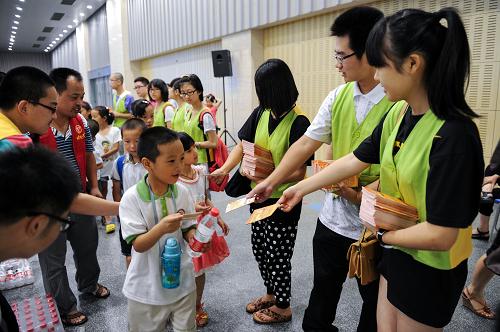7月10日,志愿者向參加夏令營的農(nóng)民工子女、社區(qū)少先隊員代表發(fā)放平安自護手冊。新華社記者 鞠煥宗 攝